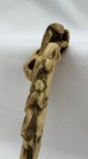 A Japanese stag antler parasol handle carved with a bird atop a tree with a monkey climbing upwards,