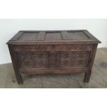 An 18th century oak coffer the rectangular panelled top above a carved two panelled front on stiles,