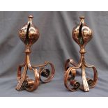 A pair of art nouveau style copper fire dogs with large seed pod shaped finials,