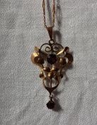 An Edwardian yellow metal pendant decorated with scrolls and flower heads on a yellow metal chain