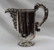A continental white metal jug cast with a mask, scrolls and leaves,