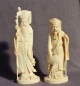 A Japanese Ivory figure of a bearded dignitary holding a staff, in a flowing robe on an oval base,