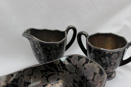 A Rockwell black glass and white metal overlay cream jug and matching twin handled sugar bowl,