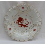 A Meissen porcelain plate with a moulded rim decorated to the centre with a red dragon,