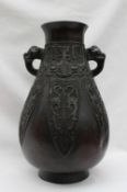 An Oriental bronze twin handled vase with a flared neck,