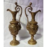 A pair of gilt bronze ewers cast with cherubs on a spreading foot,