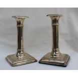 A pair of George V silver desk candlesticks with an ionic column on a square foot, London, 1917,