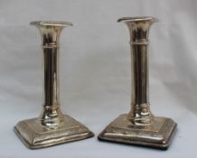 A pair of George V silver desk candlesticks with an ionic column on a square foot, London, 1917,