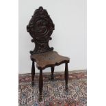 A Victorian carved oak hall chair, the shield shaped back carved with flowers, fruit and leaves,