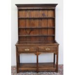 A 20th century oak dresser the moulded cornice above a rack with a planked back and three shelves,
