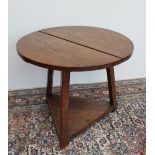 An oak cricket table, the circular top on triangular legs united by an undertier,