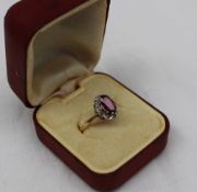 An 18ct gold ruby and diamond cluster ring, the oval shape ruby with brilliant cut diamond surround,