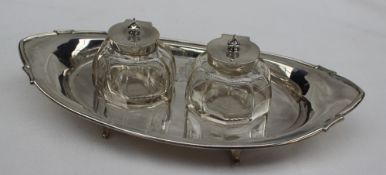 A George V silver desk inkwell, of pointed oval form set with two silver topped and glass inkwell,
