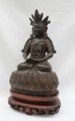 A Chinese bronze seated buddhistic figure with a crowned head, holding a box, cross legged,