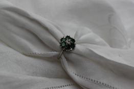 An emerald and diamond ring, the central brilliant cut diamond approximately 0.