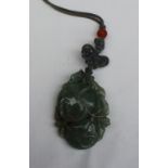 A carved jade pendant in the form of fruit and leaves on a cord necklace 55mm x 35mm