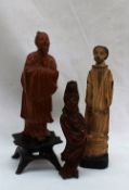 An oriental hardwood figure of a dignitary holding a sword in a long flowing robe, on a wooden base,