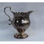 A George III silver cream jug with a flared rim and baluster body on a spreading foot, London, 1762,