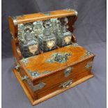 An oak tantalus, with silver plated mounts and a mirrored back, with three cut glass decanters,