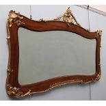A gilt decorated walnut framed wall mirror with a flower and leaf cresting,
