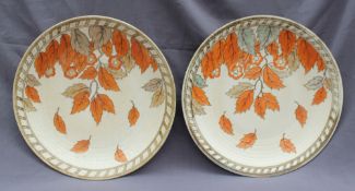 A pair of Crown Ducal Charlotte Rhead chargers decorated in fallen leaves and flowers to a cream