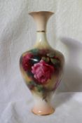 A Royal Worcester porcelain baluster vase decorated with roses to an ivory ground on a spreading