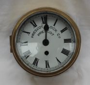 A brass bulk head timepiece, the circular dial with Roman numerals inscribed Prescot Clock Co.