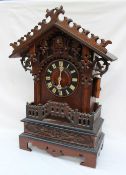 A Black Forest oak cuckoo clock the pointed arched top with pierced carving above a circular dial