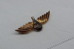 A 9ct gold jump wings badge with a central diamond set white metal parachute and two yellow metal