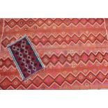 A large Persian rug decorated with geometric patterns to an orange ground,