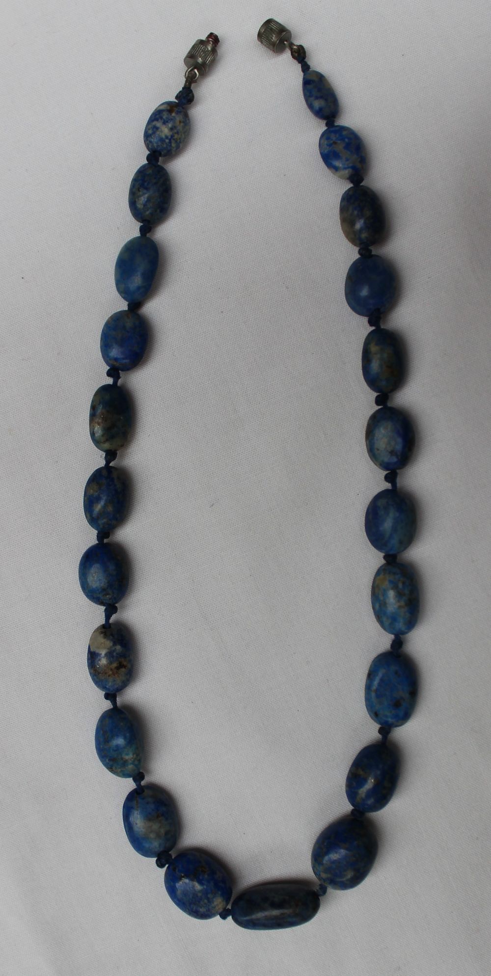 A lapis lazuli bead necklace set with irregular beads, individually knotted to a twist clasp, - Image 2 of 2