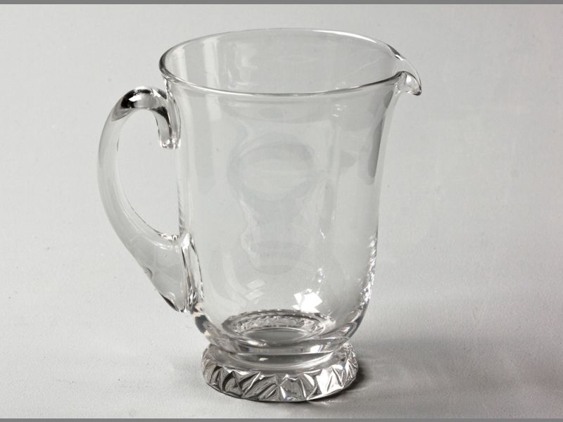 A DAUM GLASS WATER JUG with applied C-form handle, standing on a raised circular embossed base, base