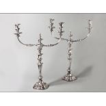 A PAIR OF SILVERPLATE THREE LIGHT CANDELABRA embossed removable wax pans, the central stem