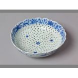 A 19TH CENTURY CHINESE EXPORT BLUE AND WHITE STRAINER DISH of lobed scalloped-form, decorated with a