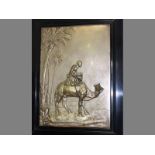 A FRAMED METAL PLAQUE DEPICTING A CAMEL AND RIDER, 38 by 26cm