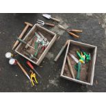 A selection of garden hand tools and two wooden boxes.