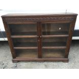 An oak arts and crafts floor standing bookcase with glass doors and adjustable shelving.