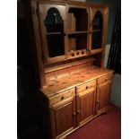A Ducal pine dresser with glass door display cupboards to the top and three drawers over three