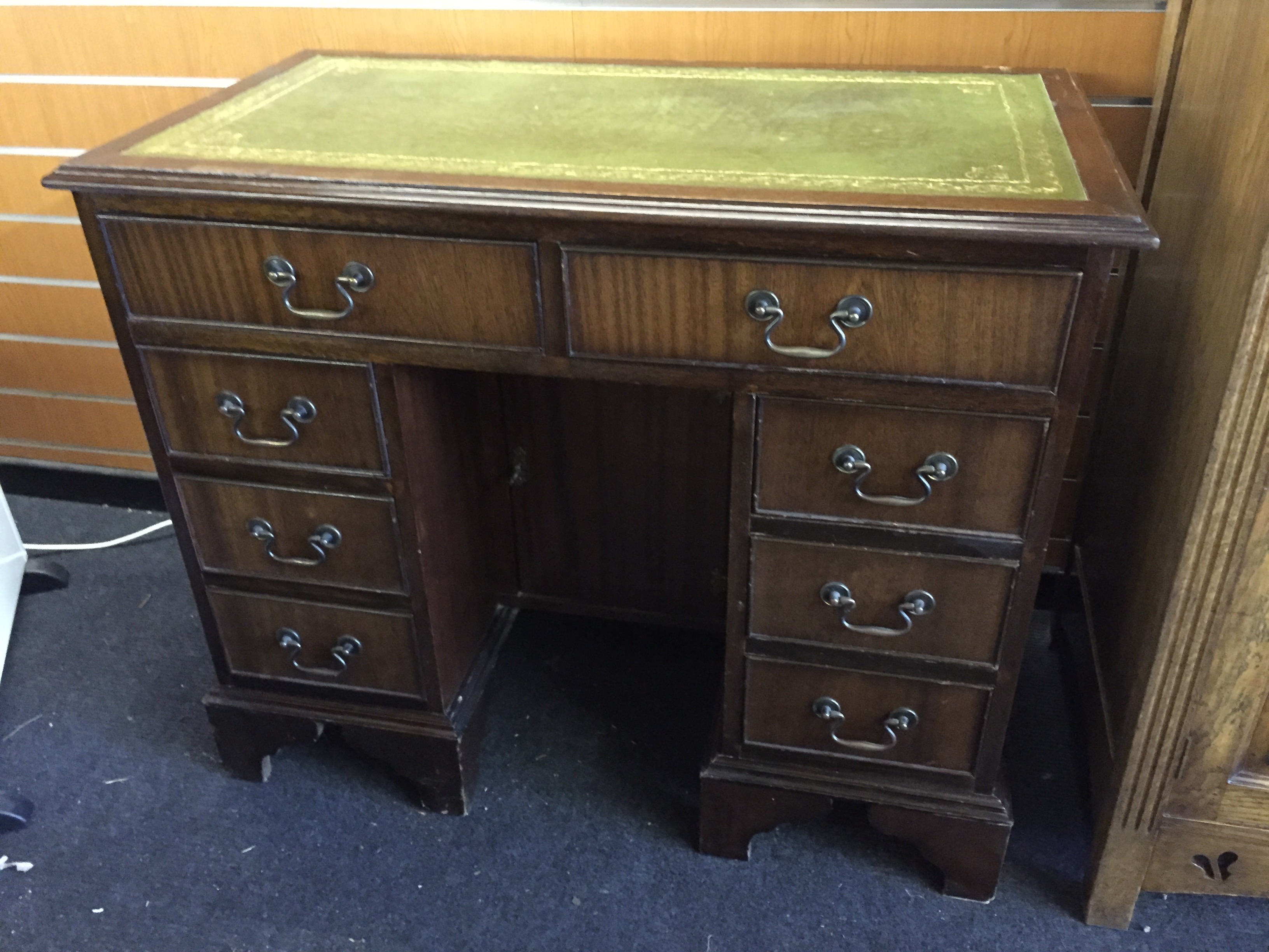 A small pedestal desk with green leather top and two long drawers with three drawers to each