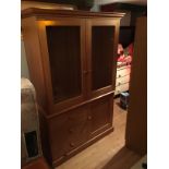 A handmade oak cupboard with adjustable shelving with glass doors above two cupboards.