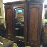 A large sectional Victorian triple wardrobe with central mirror.