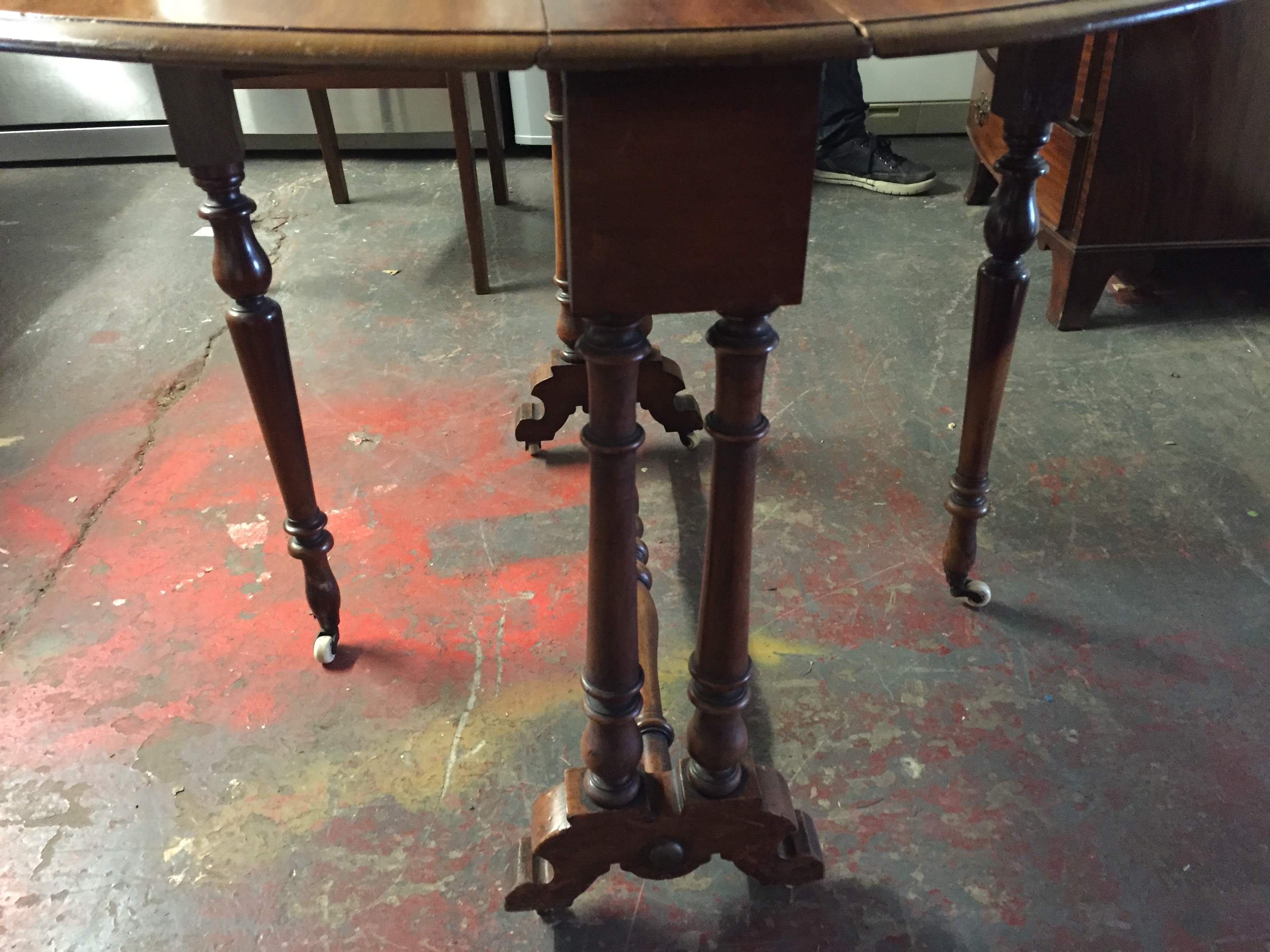 A Sutherland style circular table with turned legs and stretchers on porcelain castors. - Image 2 of 2