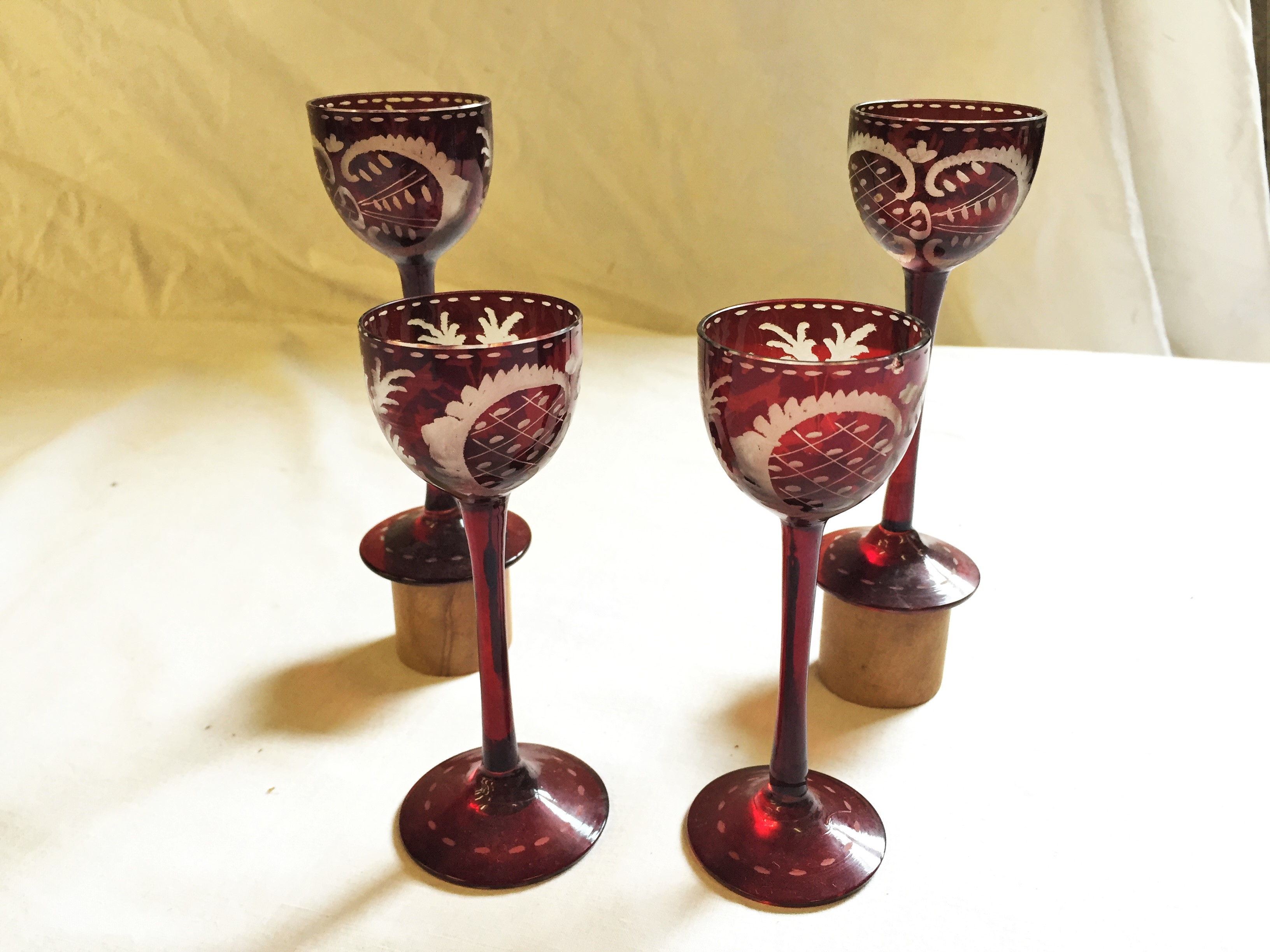 Four Bohemian ruby etched liquor glasses.