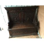 A Highly carved monk's bench having a two carved panel back featuring cherubs and foliage with