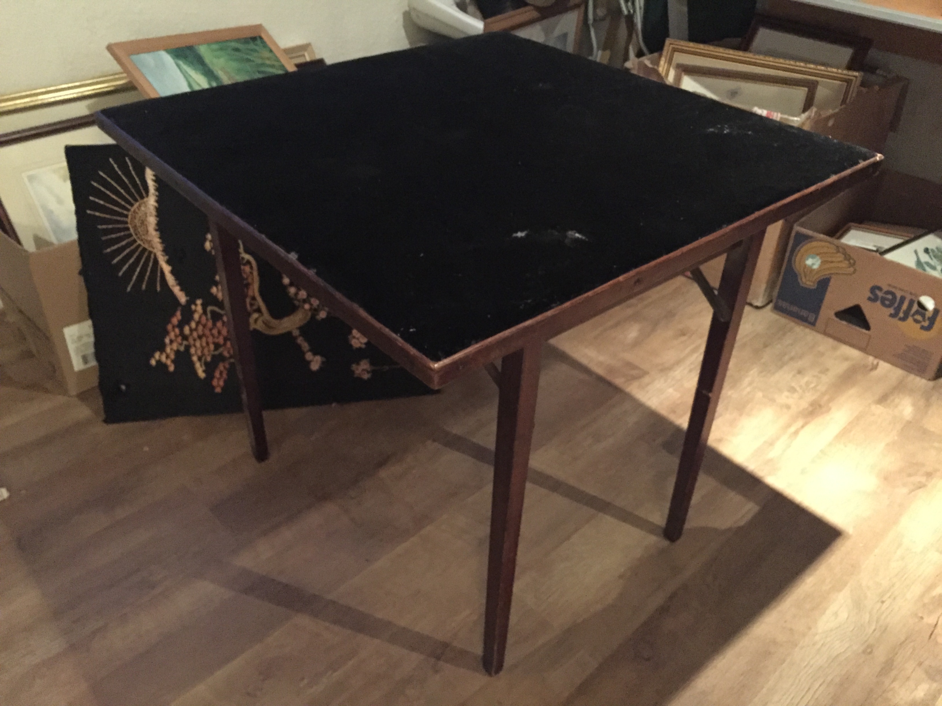 A folding card table with beige top.