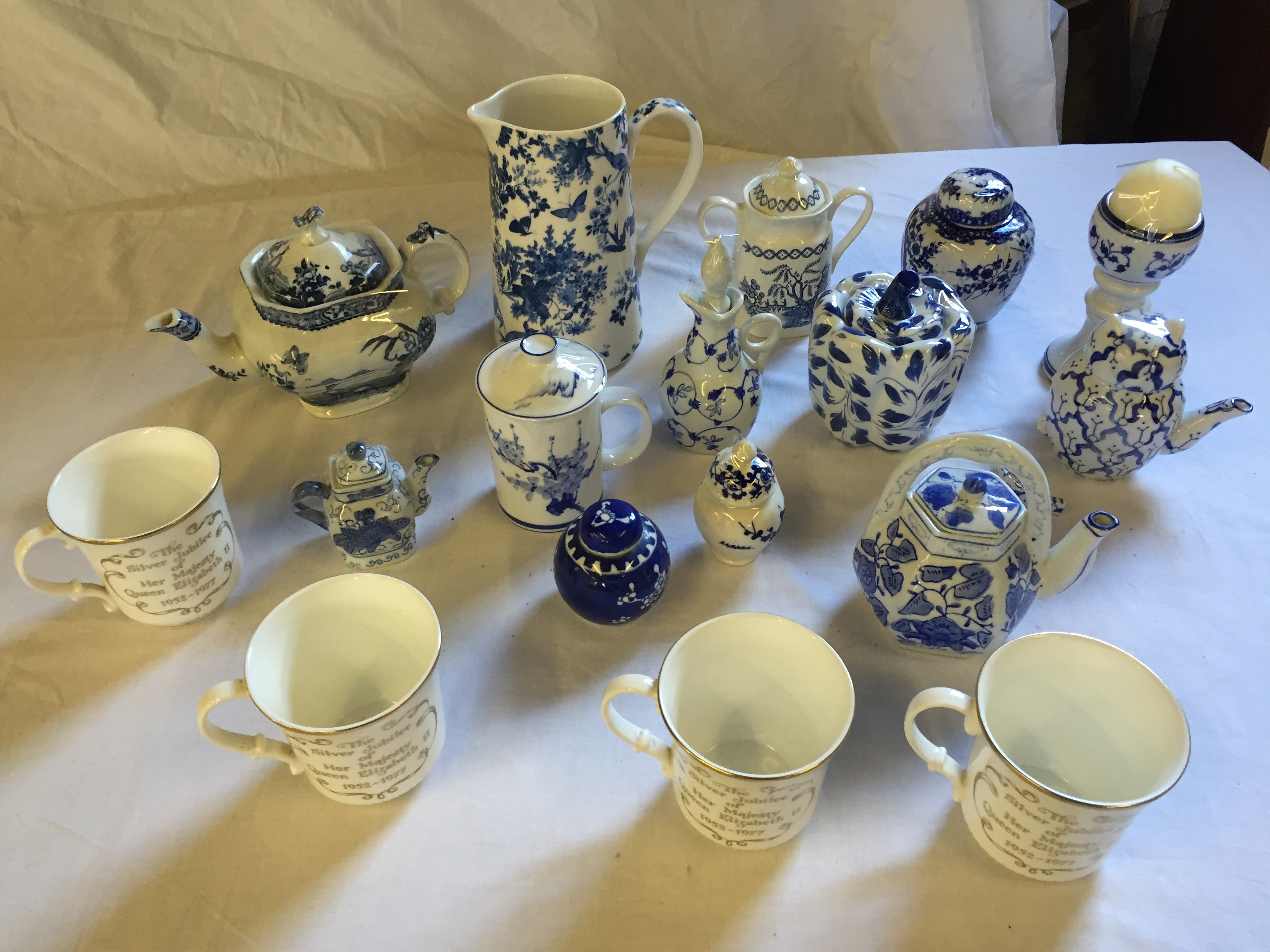 Blue and white ceramics including commemorative mugs.