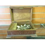 A carved wooden box depicting elephants and containing silver plate.