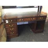 A leather top pedestal desk with long central drawer and four short drawers to the left and one