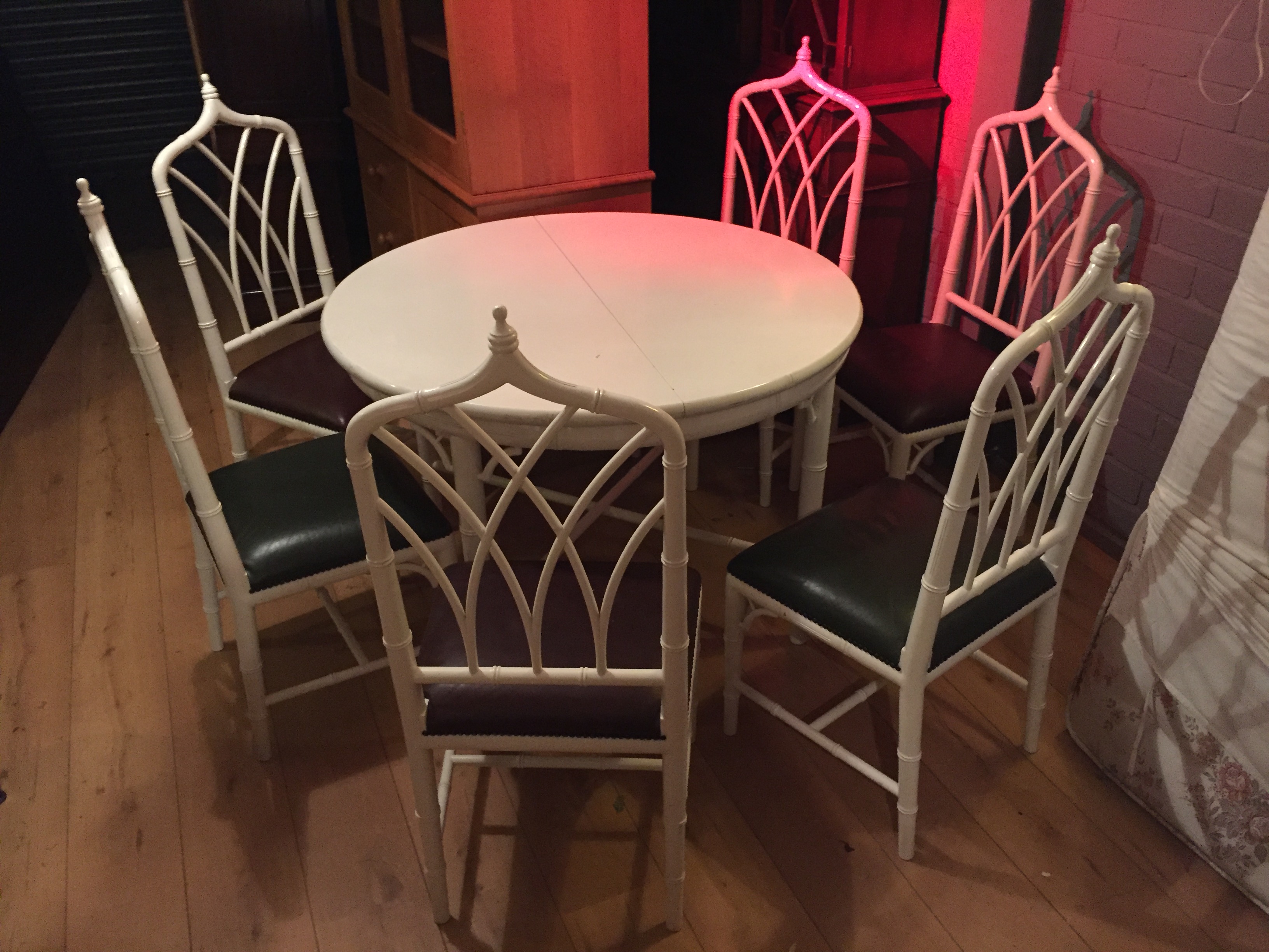 A circular extending dining table and six cane cathedral back chairs.