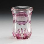 Biedermeier-Andenkenbecher. Böhmen, um 1850. Farbloses, teils rosa gebeiztes Glas. Facettierter